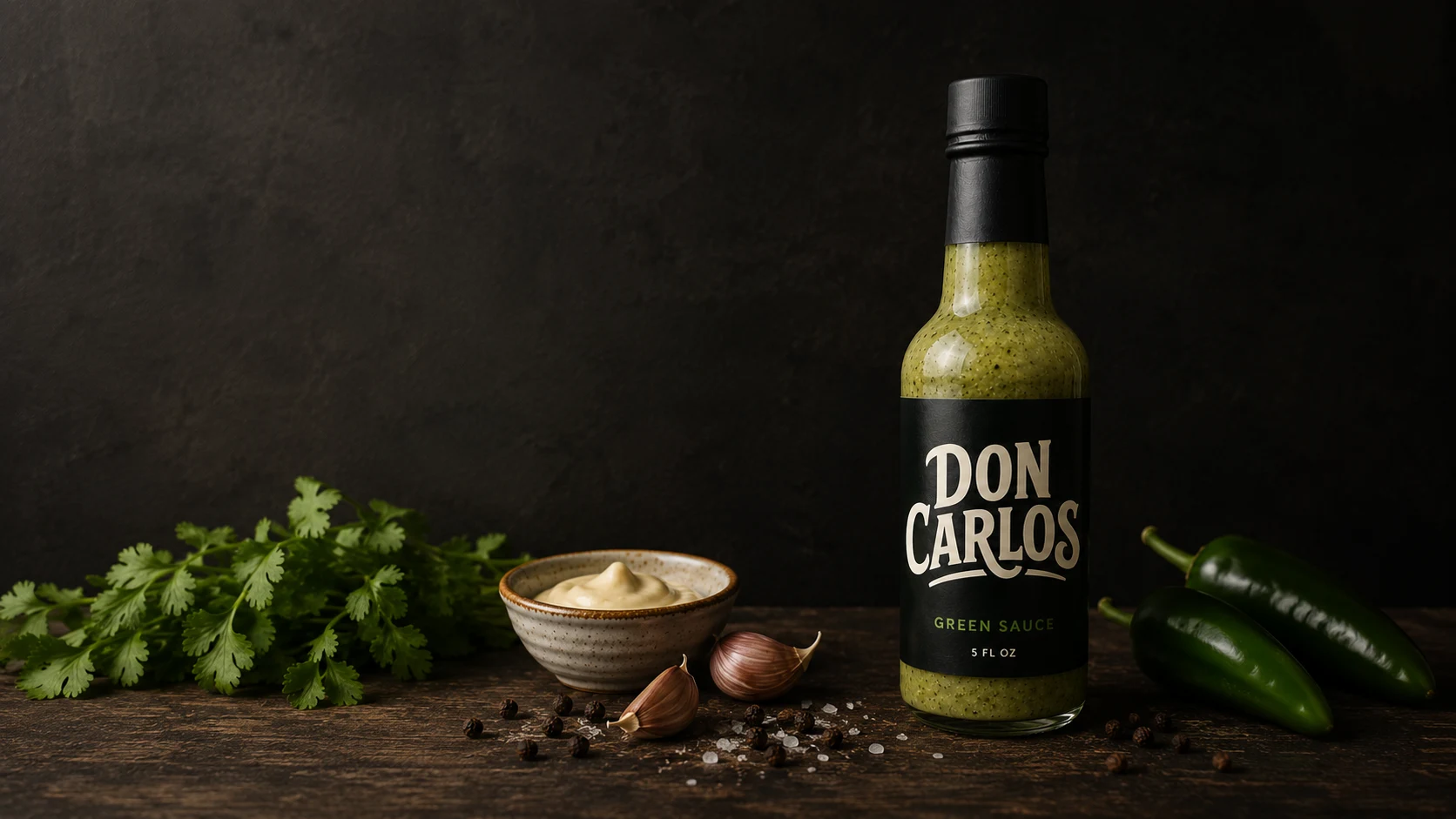 Don Carlos Green Sauce bottle with cilantro, garlic, jalapeño, and black pepper on a dark studio backdrop